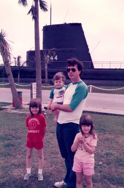 With a submarine in the background, I hold Aaron in 1985 at Seawolf Park in Galveston, Texas, with his older sisters along on the trip.